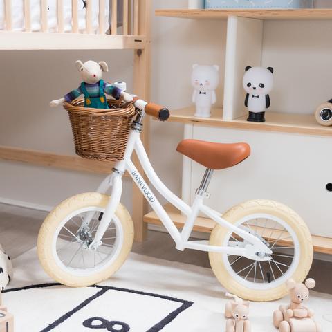 Bicicletta senza pedali Banwood First Go bianca posizionata in una cameretta per bambini, perfetta come regalo e arredo dallo stile retrò