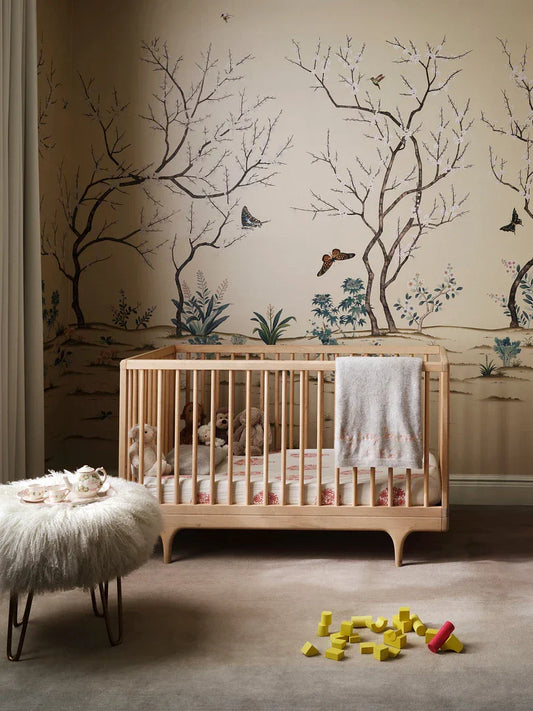 Culla Caravan Crib di Kalon in una cameretta moderna, realizzata in legno naturale con design minimalista e sostenibile