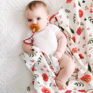 Neonata sdraiato su un telo swaddle colorato in mussola di cotone