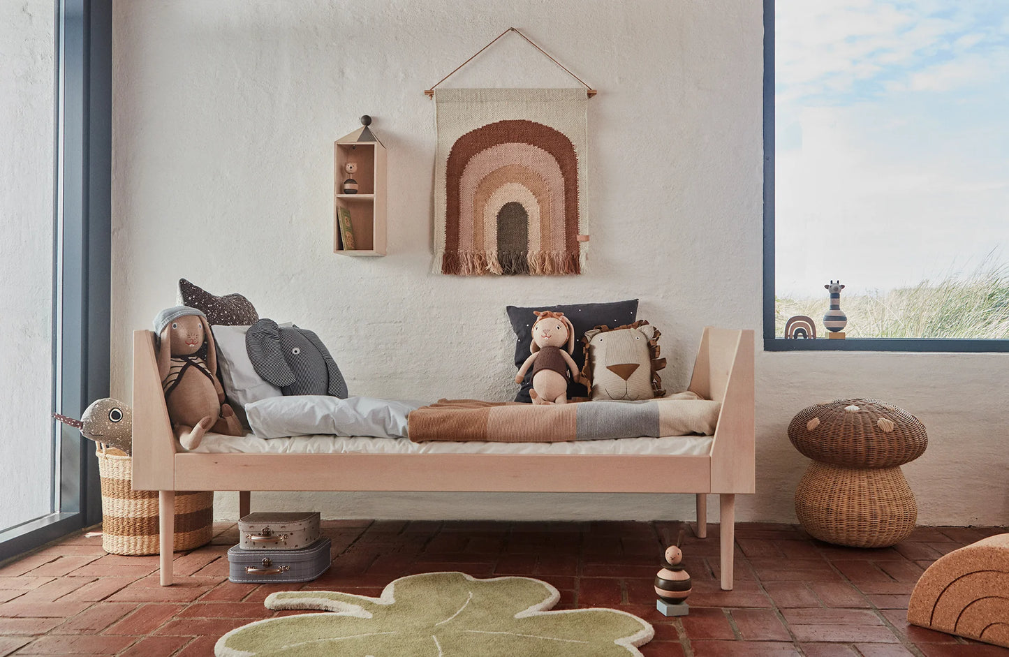 Decorazione da parete OYOY a forma di arcobaleno in una cameretta con giochi e mobili in legno