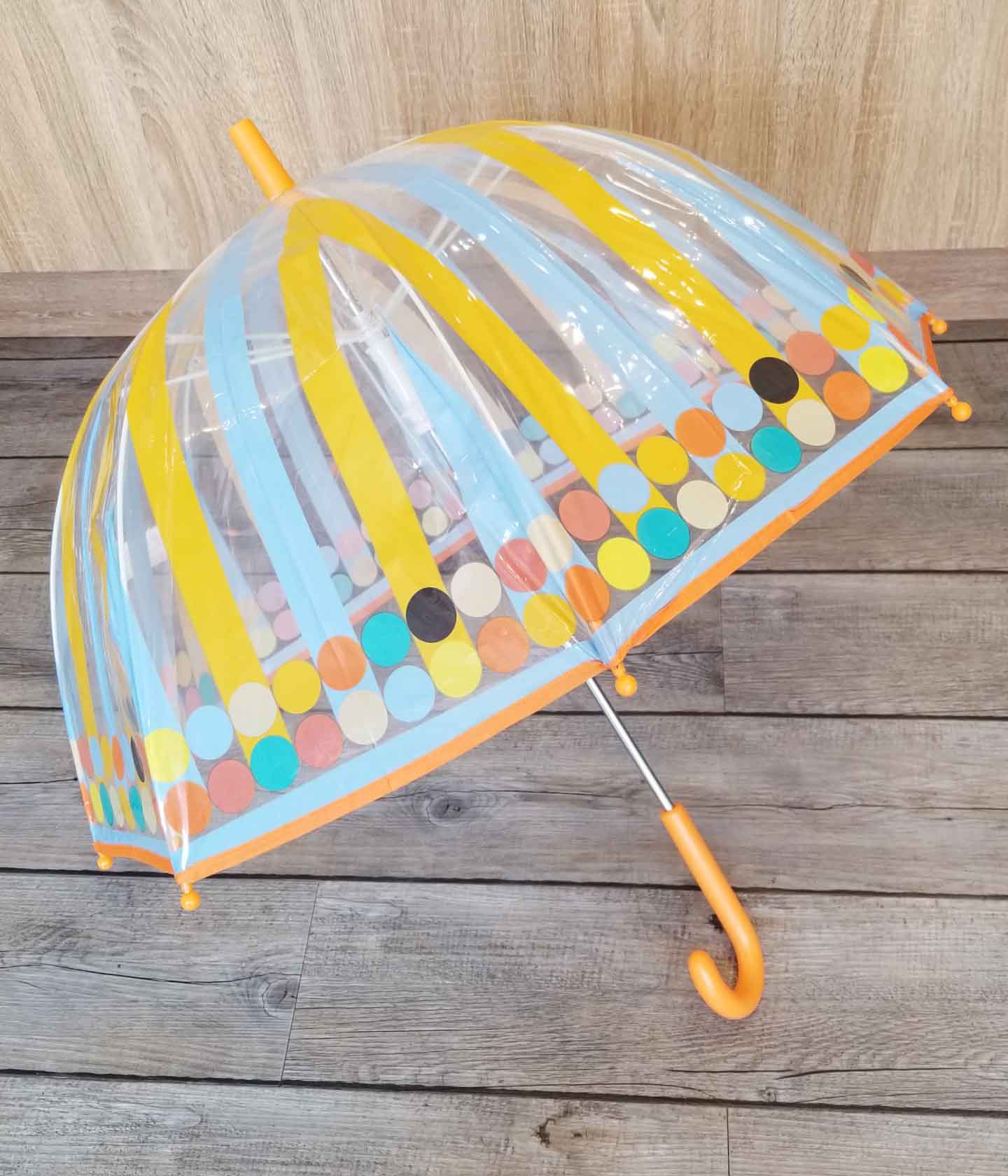 Ombrello Djeco Graphic medio con fantasia geometrica, chiuso e appoggiato su un pavimento in legno