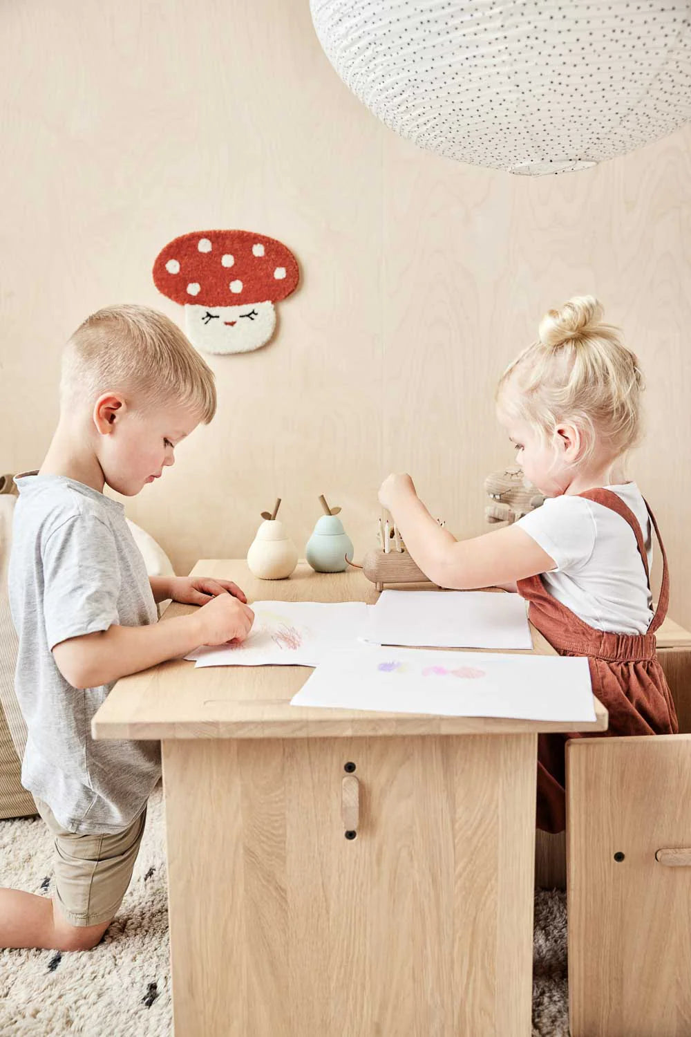 Due bambini giocano in una cameretta con decorazione a parete OYOY Mini a forma di fungo