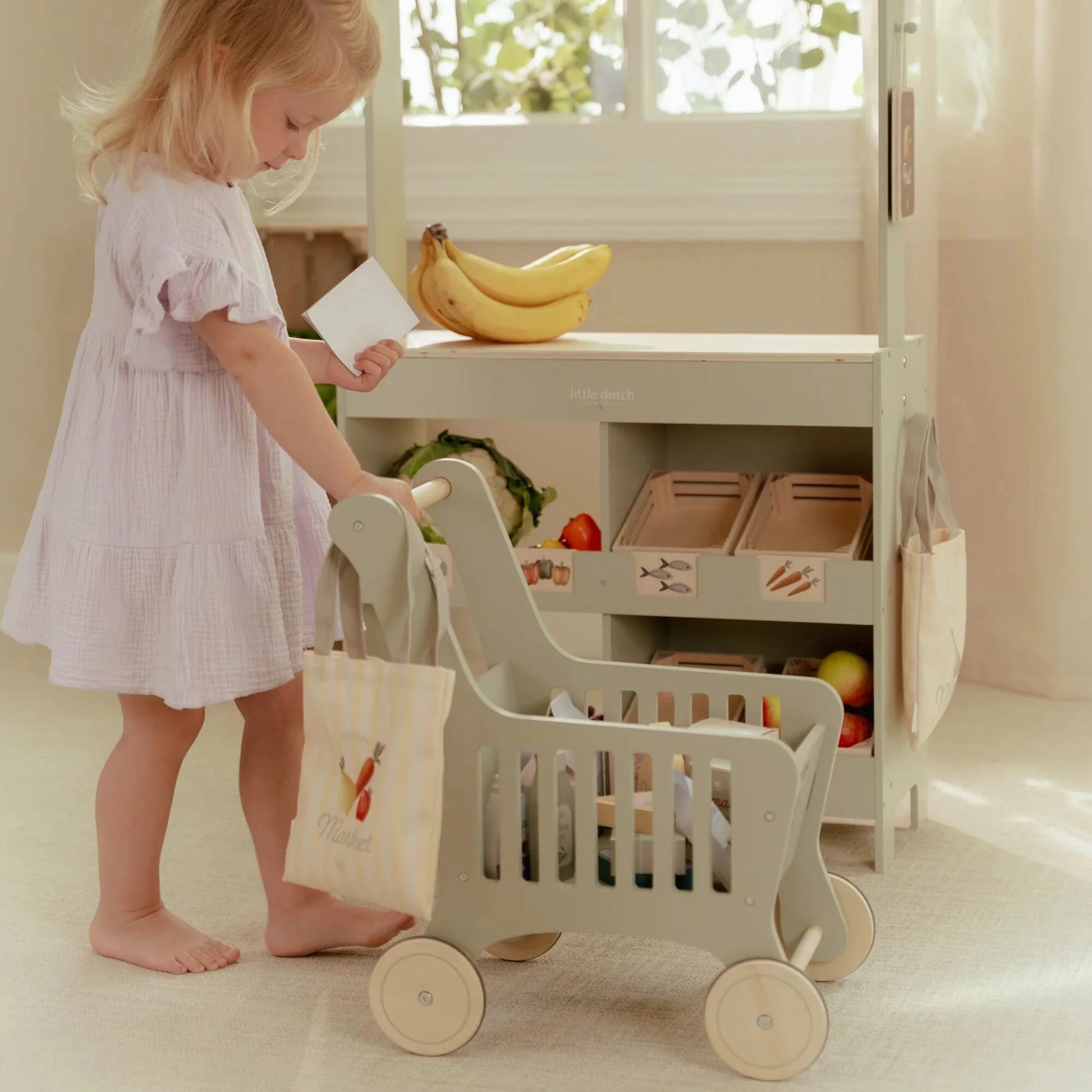 Bambina gioca con il carrello della spesa in legno Little Dutch