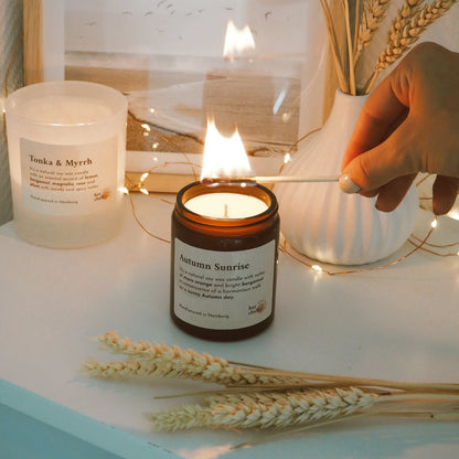 Candela Hey Chalky Autumn Sunrise accesa su tavolo con atmosfera autunnale e luce calda