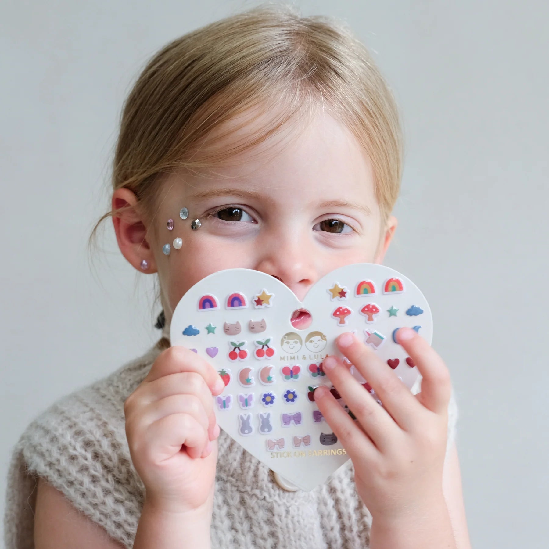 Bambina che indossa gli orecchini adesivi Mimi & Lula Mixed Novelty colorati e giocosi