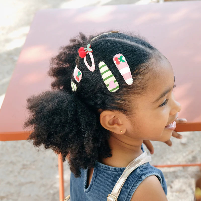 Bambina con mollette a forma di ciliegia nei capelli acconciatura estiva colorata