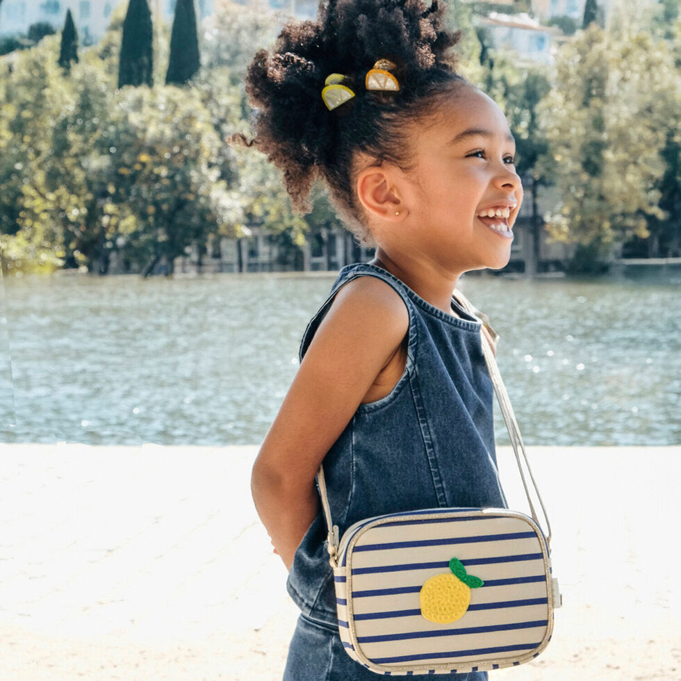 Bambina con borsetta Rockahula Lemon Drop a righe blu in look estivo