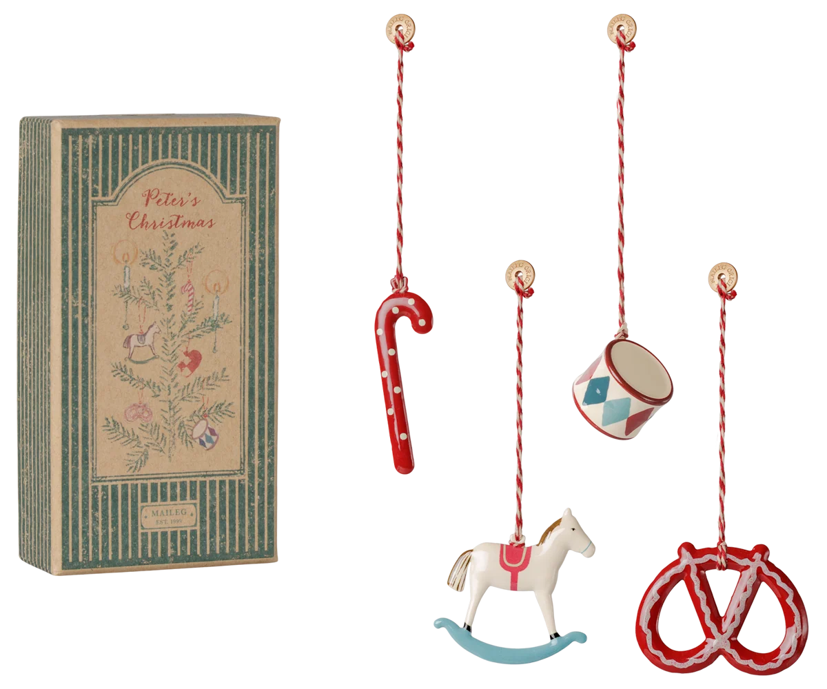 Set di 4 ornamenti natalizi Maileg Peter's Christmas in metallo con tamburo, canna di zucchero, pretzel e cavallo a dondolo in confezione regalo illustrata.