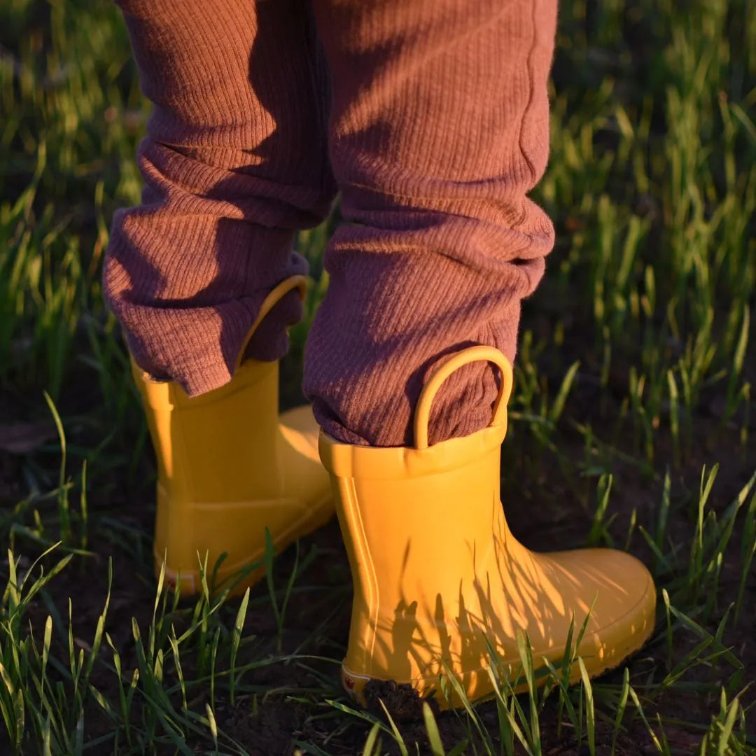 Bambino indossa stivaletti pioggia Mr Tiggle giallo opaco sotto la pioggia