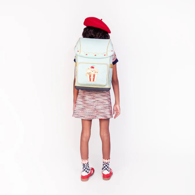 Bambino con zaino Jeune Premier Popcorn sulle spalle davanti a scuola